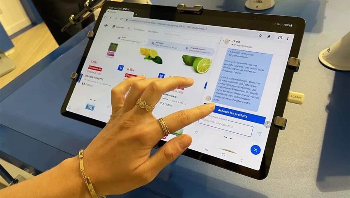 A hand tapping a grocery app on a tablet, where an assistant thread is adding limes to a basket.