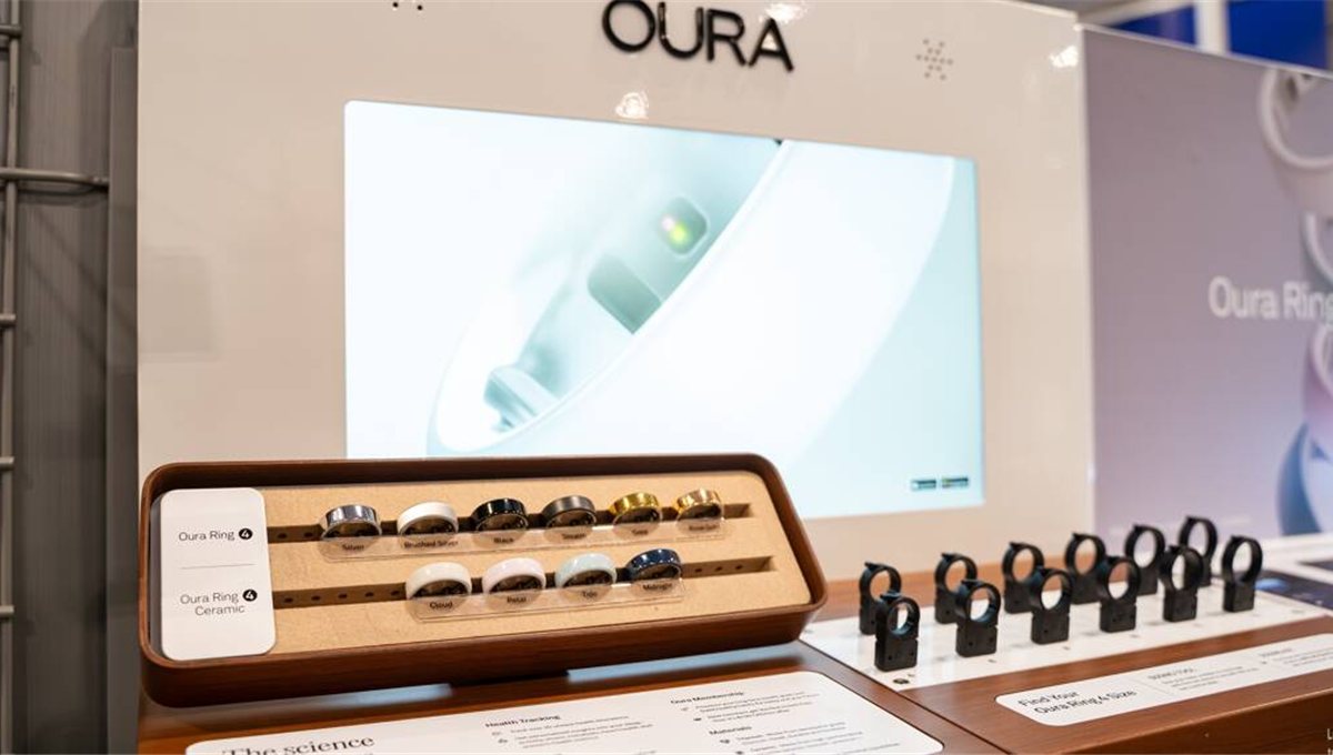 A retail display of Oura rings in a row of finishes under a lit screen.