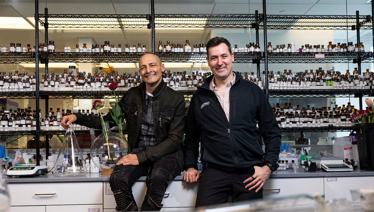 Two of Osmo's founders sitting in front of shelves of laboratory scent bottles.