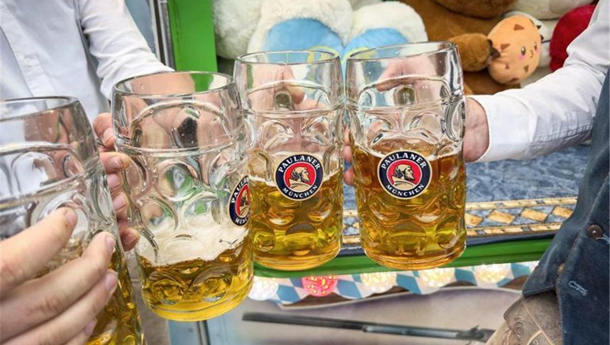 Four Paulaner beer steins held up together at Oktoberfest.