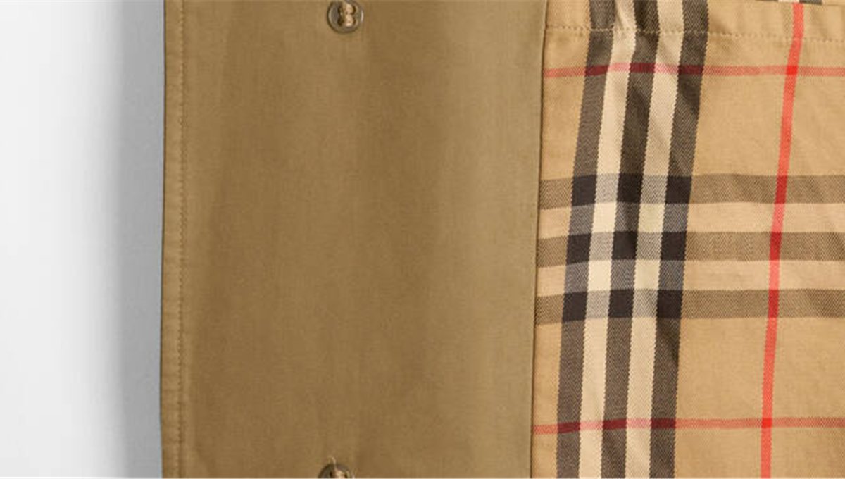 A close detail of a Burberry trench coat showing the gabardine and the check lining.