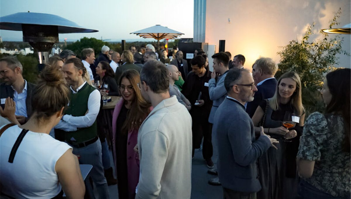 Guests talking on the Rischart rooftop terrace above the Theresienwiese at dusk.