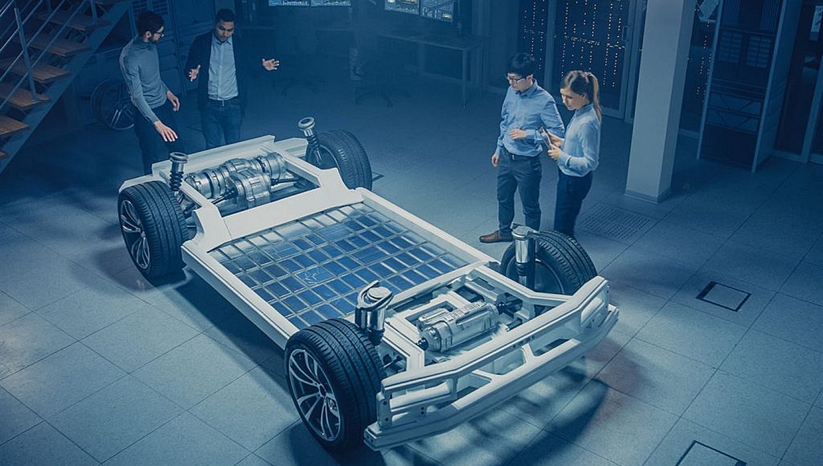 Engineers around an electric vehicle chassis in a development lab