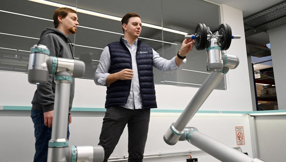 Two RobCo employees with one of the company's robot arms