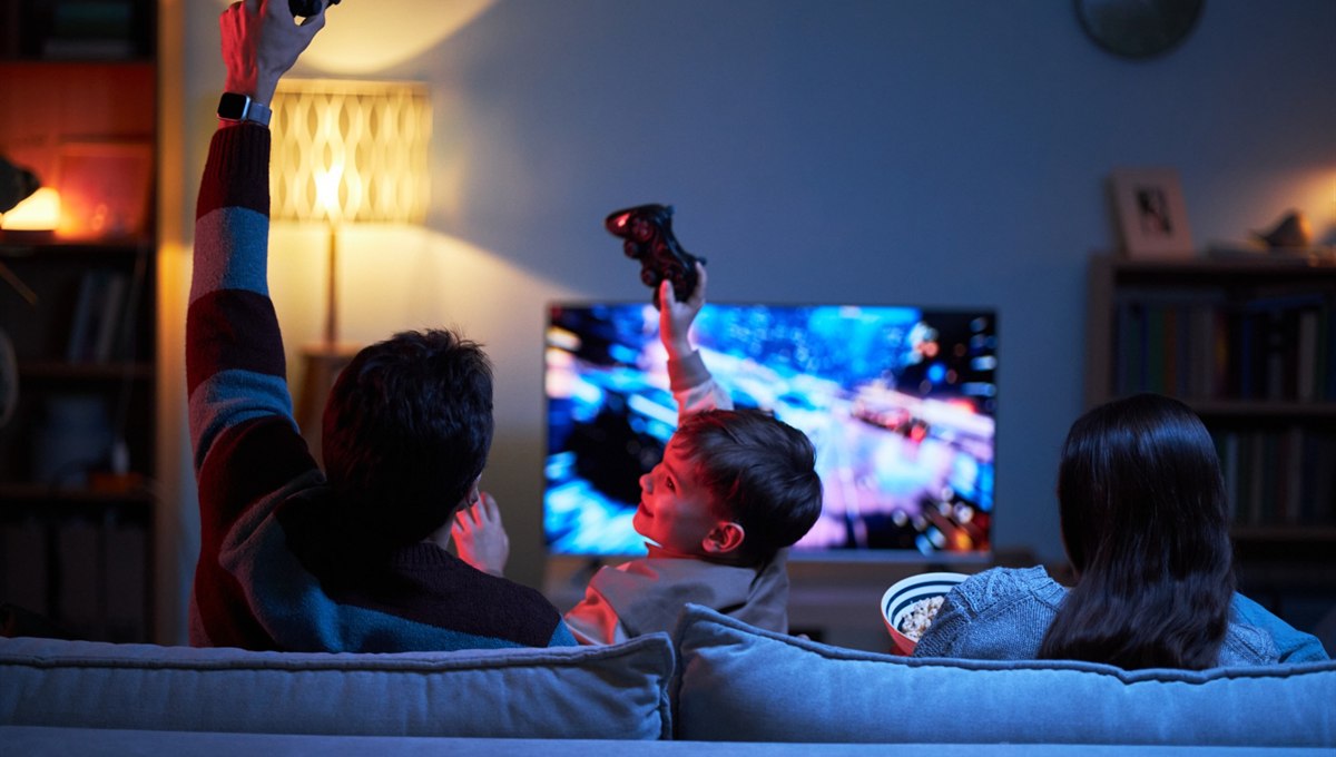 A family on a sofa playing a video game together in the evening.